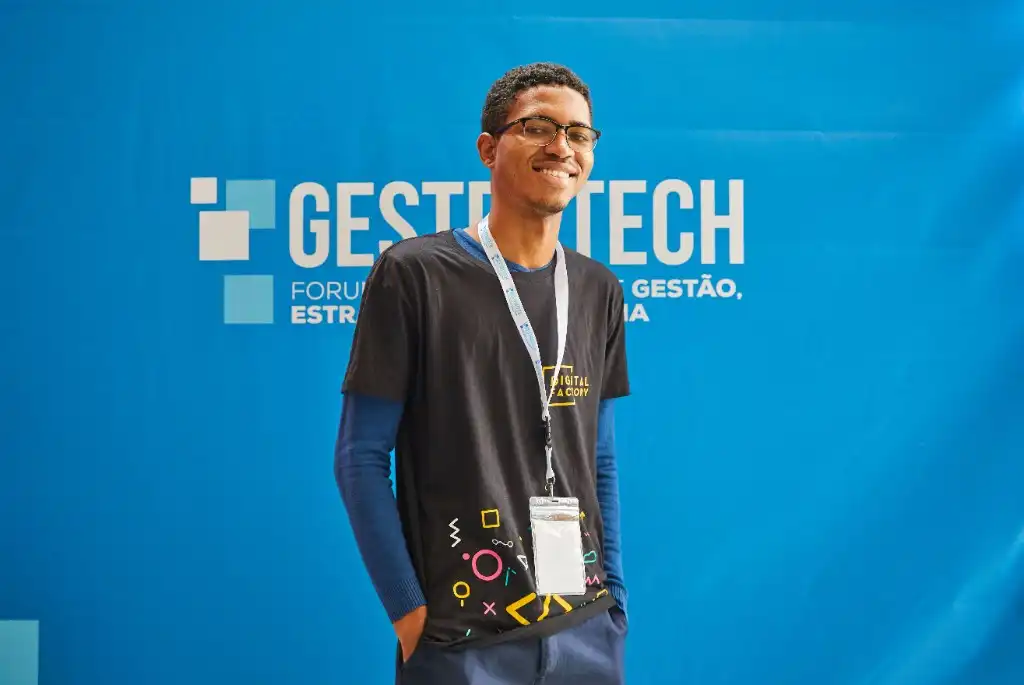 Jovem aprendiz sorrindo com crachá em ambiente profissional de formação