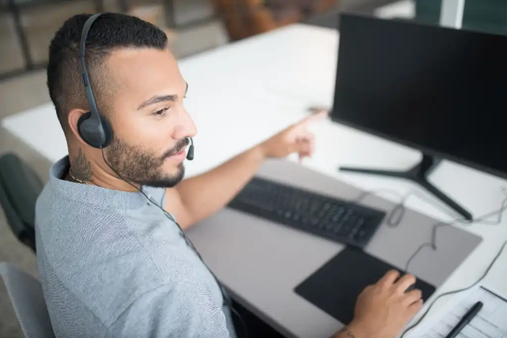Profissional de tecnologia com headset operando computador em ambiente corporativo de TI